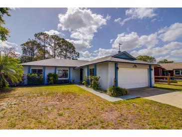 Charming single-story home featuring a two-car garage, blue trim, and well-maintained landscaping at 2729 Hilda Ct, Orlando, FL 32826