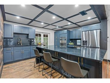 Modern kitchen with blue cabinets, granite countertops, stainless steel appliances and breakfast bar with seating at 409 San Sebastian Prado, Altamonte Springs, FL 32714