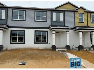 Two-story townhome featuring neutral colored siding, white trim, and a covered entryway at 628 Pothos St, Apopka, FL 32703