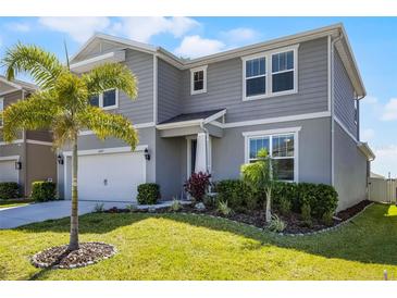 Charming two-story home with a manicured lawn, lush landscaping, and attached garage at 7649 Ragusa Way, Clermont, FL 34714