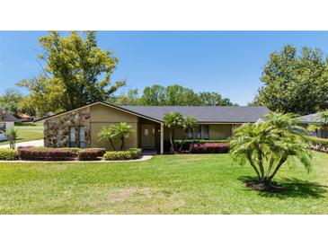 Charming single-story home featuring stone accents, a well-manicured lawn, and mature landscaping at 7655 Persian Ct, Orlando, FL 32819