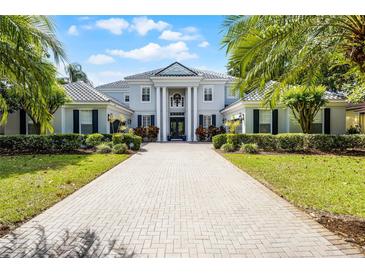 Stately two-story home with a columned entrance, gray exterior, manicured landscaping, and a paver driveway at 11014 Hawkshead Ct, Windermere, FL 34786