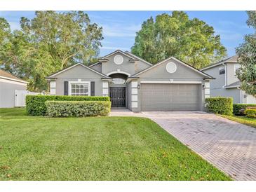 Charming single-Gathering home featuring a paved driveway, lush lawn, and mature trees at 131 Calabria Springs Cv, Sanford, FL 32771