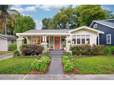 Charming bungalow with lush landscaping, featuring colorful flowers and a welcoming orange front door at 14 N Lawsona Blvd, Orlando, FL 32801