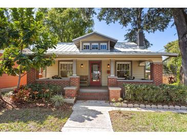 Charming home featuring a red door, covered porch, and well-manicured landscaping at 210 E Kaley St, Orlando, FL 32806