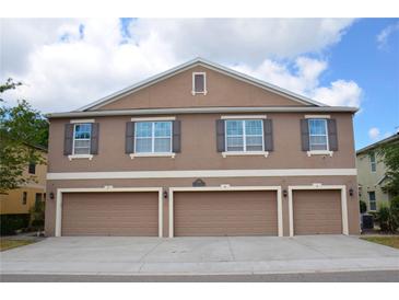 Three-story townhouse featuring three single-car garages and symmetrical window placement with shutters at 3416 Seneca Club Loop # 56, Orlando, FL 32808
