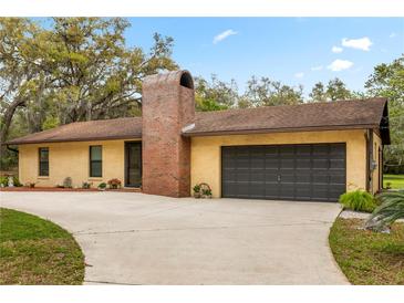 Single story home with a brick chimney, two car garage, and a concrete driveway at 4495 Bedford Rd, Sanford, FL 32773