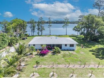 Charming single-story home featuring a picturesque lake view and lush landscaping at 7420 Lake Willis Dr, Orlando, FL 32821