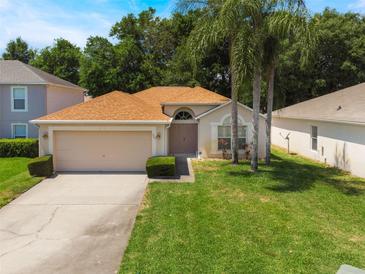 Charming single-story home featuring a well-maintained lawn, attached garage, and tropical palm trees at 122 Oak View Pl, Sanford, FL 32773
