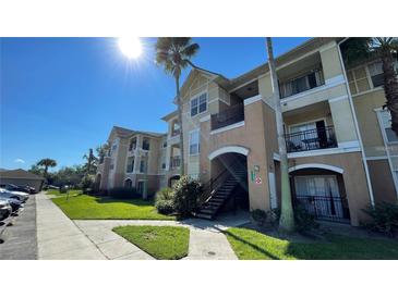 Tan stucco condos with balconies, palm trees, and landscaped grounds on a sunny day at 3702 Palm Desert Ln # 5435, Orlando, FL 32839