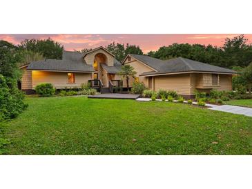 Charming home with manicured lawn, deck, and inviting entryway at sunset at 1555 Waterwitch Dr, Orlando, FL 32806
