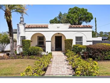 Inviting home displaying tidy landscaping, a brick pathway, and an attractive arched entryway at 2107 Delaney Ave, Orlando, FL 32806