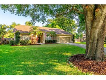 Inviting single-story home with a manicured lawn, mature trees, and well-maintained landscaping at 3509 Battersea Ct, Belle Isle, FL 32812