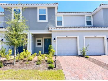 Charming townhome featuring a well-maintained lawn, brick driveway, attached garages, and a serene, light gray color palette at 3623 Main Harbor Dr, Kissimmee, FL 34746