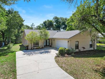 Charming single-story home with a well-maintained lawn, mature trees and long concrete driveway at 510 N Leavitt Ave, Orange City, FL 32763