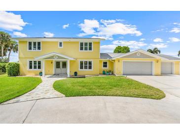 Bright yellow two-story home featuring a spacious lawn and attached two-car garage at 5224 Saint Regis Pl, Belle Isle, FL 32812