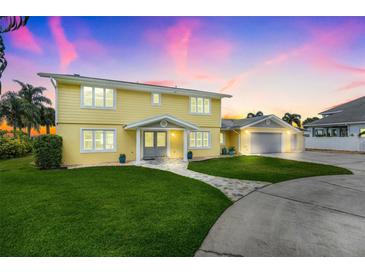 Beautiful two-story yellow home with a well-manicured lawn, elegant walkway, and an attached two-car garage at 5224 Saint Regis Pl, Belle Isle, FL 32812