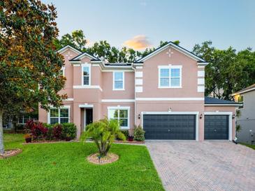 Charming two-story home boasts a well-maintained lawn, lush landscaping, and a three-car garage at 925 Counts Crest Cir, Apopka, FL 32712