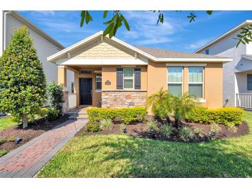 Charming single-story home with a stone facade, manicured lawn, and inviting front porch at 9456 Komika Ln, Winter Garden, FL 34787