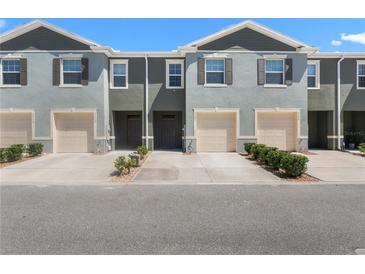 Charming townhomes featuring neutral exteriors, garages, and manicured landscaping under a clear blue sky at 1121 Blue Jay Dr, Davenport, FL 33837