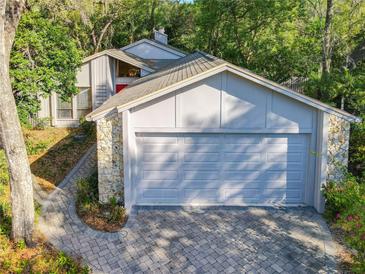 Spacious garage with stone accents and a paved driveway nestled among mature trees at 136 Bridgeview Ct, Longwood, FL 32779