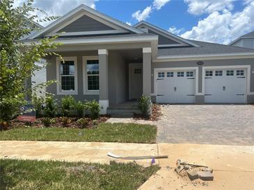 Charming single-Gathering home featuring a two-car garage, well-manicured lawn, and inviting front porch at 16759 Muskgrass Dr, Winter Garden, FL 34787