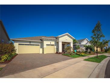Inviting home exterior features a two-car garage, paver driveway, and beautifully landscaped yard under a clear blue sky at 2458 Dream Home Ct, St Cloud, FL 34772
