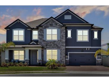 Charming two-story home featuring a stone facade, gray paint, and a two-car garage at dusk at 2628 Cedar Shake Ct, Oviedo, FL 32765
