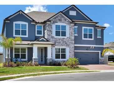 Charming two-story home featuring a stone facade, gray paint, and a two-car garage at 2628 Cedar Shake Ct, Oviedo, FL 32765