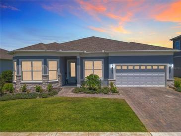 Beautiful single-story home featuring a two-car garage, manicured lawn, and a charming brick walkway at 3182 Sailing Pier Ave, Winter Garden, FL 34787