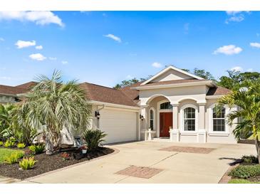 Charming home featuring a red door, meticulously landscaped yard with palm trees, and an attached two-car garage at 3375 Bellino Blvd., New Smyrna Beach, FL 32168