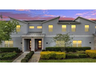 Charming townhome with a modern facade, red door, covered entry, and professionally landscaped front yard at 368 Ocean Course Ave, Davenport, FL 33896