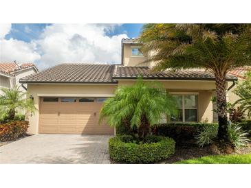 Charming two-story home with a well-manicured lawn, palm trees, and a two-car garage at 9895 Winnington St, Orlando, FL 32832
