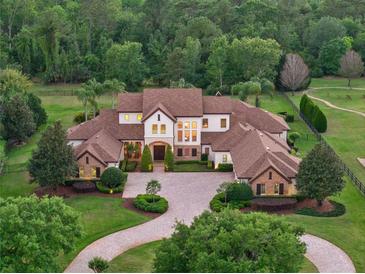 Stunning estate home featuring lush landscaping, grand entrance, and a sprawling tree-lined property at 1526 Bluewater Run, Chuluota, FL 32766