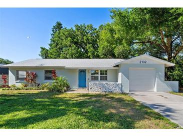 Charming single-story home with a blue front door, lush landscaping and an attached garage at 2132 Rouse Lake Rd, Orlando, FL 32817