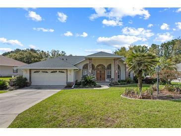 Charming single-story home with a well-manicured lawn, arched windows, and a two-car garage at 58 Golf View Dr, Ocala, FL 34472