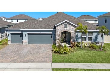 Beautiful single-Gathering home with a paver driveway, stone accents, and a well-manicured lawn at 690 Blue Citrus Ln, Minneola, FL 34715