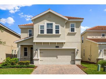 Charming two-story home with a well-manicured lawn and a brick paved driveway leading to the garage at 8991 Fluffy Lie Ct, Davenport, FL 33896