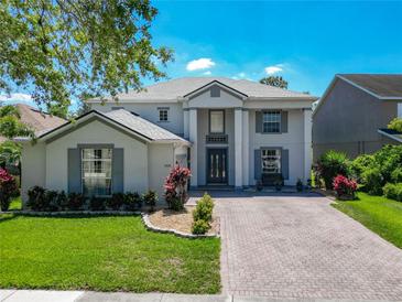 Charming two-story home featuring a well-manicured lawn, brick driveway, and a welcoming entrance at 9076 Lake Avon Dr, Orlando, FL 32829