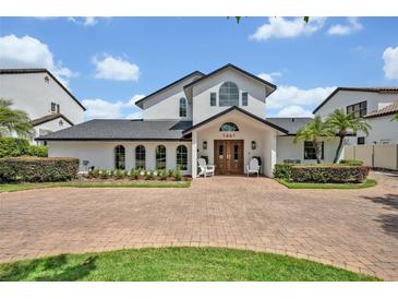 Stunning two-story home featuring a pristine white facade, manicured landscaping, and a circular brick driveway at 1661 Woodland Ave, Winter Park, FL 32789