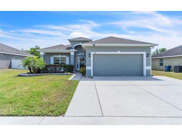 Charming single-story home featuring a manicured lawn, gray exterior paint, and a two-car garage at 344 Highland Meadows St, Davenport, FL 33837