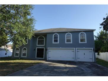 Charming two-story home with a three-car garage and arched windows against a clear blue sky at 459 Danube Dr, Poinciana, FL 34759