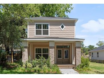 Charming two-story home with a covered front porch, brick accents and manicured landscaping at 805 S Locust Ave, Sanford, FL 32771