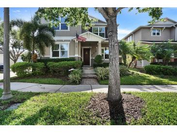 Inviting two-story home with a well-manicured lawn, lush landscaping, and covered entryway with decorative touches at 8111 Pacific Loon St, Winter Garden, FL 34787