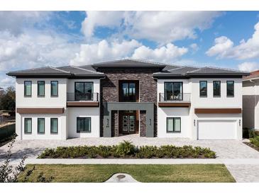 Beautiful modern two-story home with stone accents, a tile roof, and manicured landscaping at 1014 Jack Nicklaus Ct, Reunion, FL 34747
