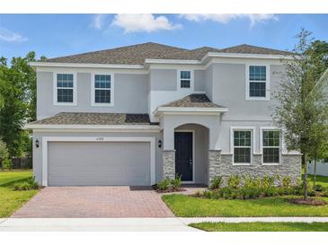 Charming two-story home with gray siding, stone accents, and manicured front yard at 1169 Happy Forest Loop, Deland, FL 32720