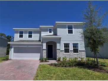 Charming two-story home featuring a two-car garage, stone accents, and well-manicured lawn at 1169 Happy Forest Loop, Deland, FL 32720