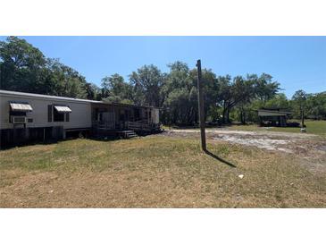 Exterior shot of the home with a large yard and additional outdoor structures at 1275 Arapaho Trl, Geneva, FL 32732
