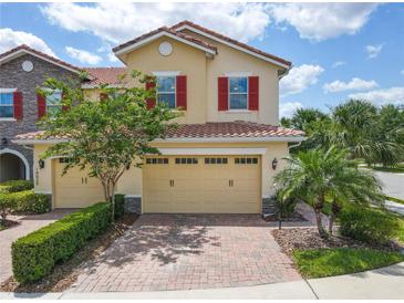 Charming townhome with red shutters, tile roof, two-car garage, and a brick driveway at 14014 Millington St, Orlando, FL 32832