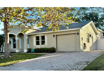 Beige home featuring an attached garage and beautiful brick paver driveway at 145 Burns Ave, Longwood, FL 32750